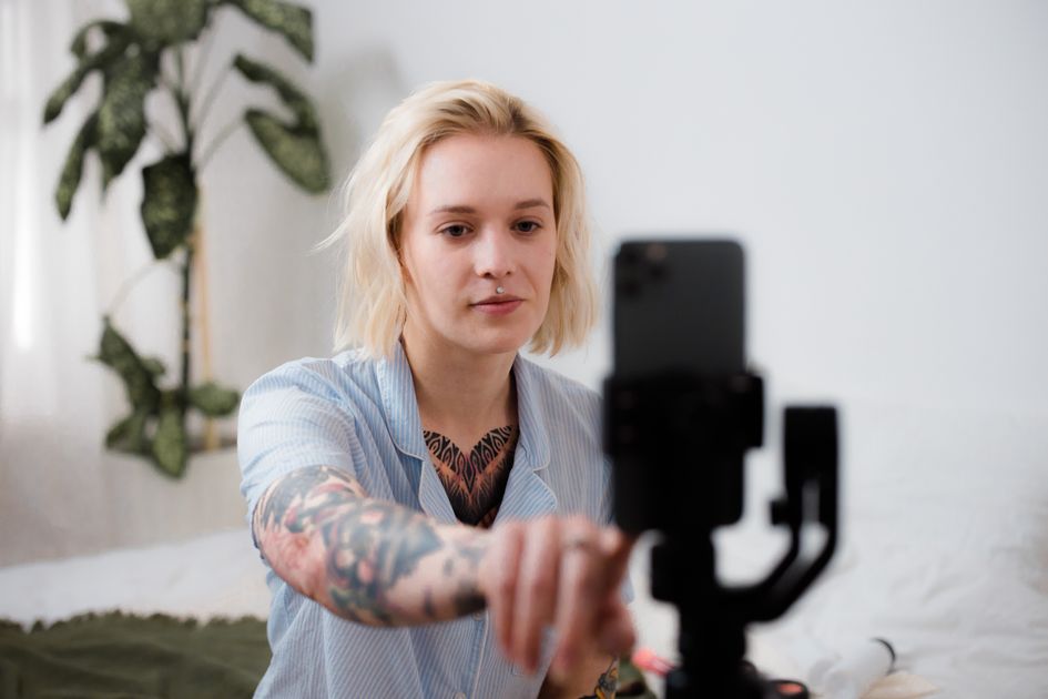 A person adjusting a smartphone on a tripod to film