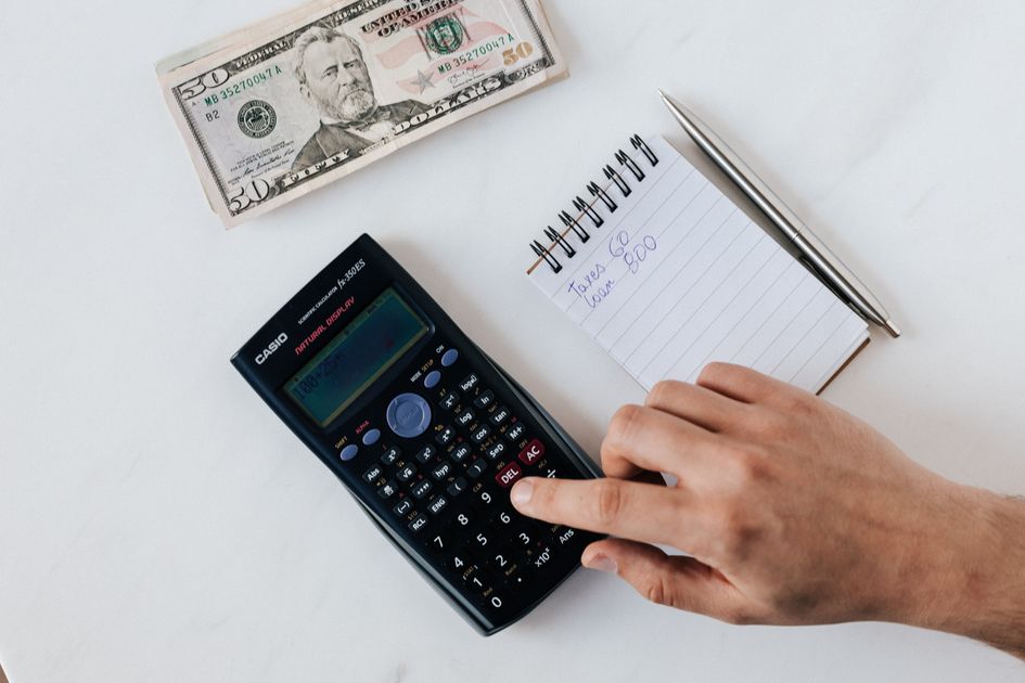 An economist calculating with a pile of dollar banknotes nearby