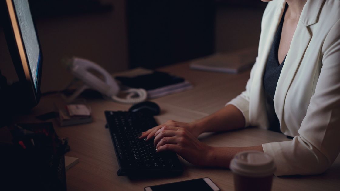 A woman typing on a keyboard late at night in an office