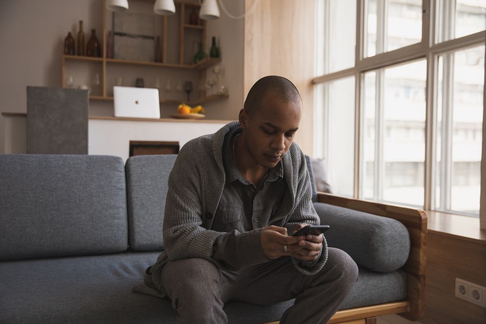 A man relaxing on a sofa surfing the internet on his phone