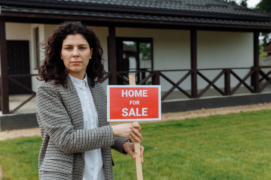 A confident real estate agent holding a sign