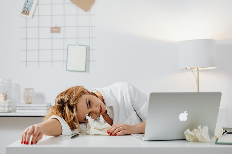 An exhausted freelancer resting at their desk with a laptop