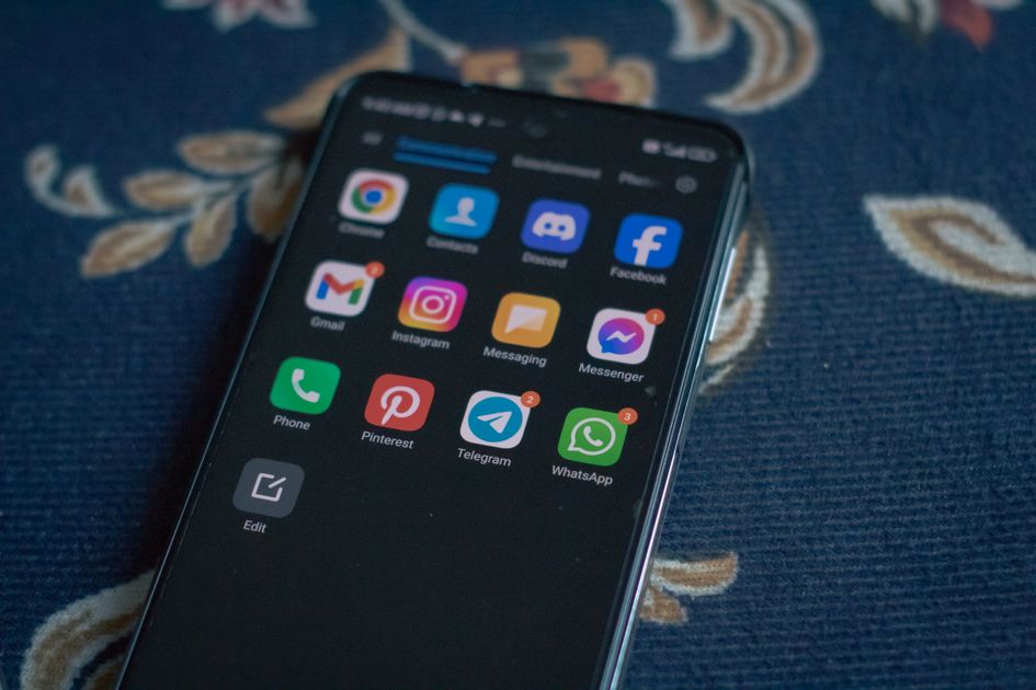 A smartphone displaying social media apps on a fabric surface