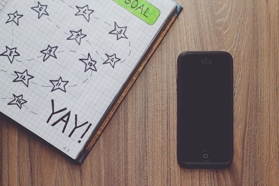 A notebook with a star drawing and a phone on a wooden desk